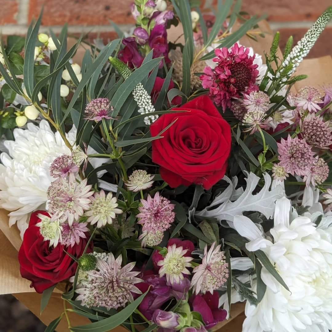 festive Christmas flower bouquet red roses white blooms eucalyptus purple aster gift wrapped with brown paper