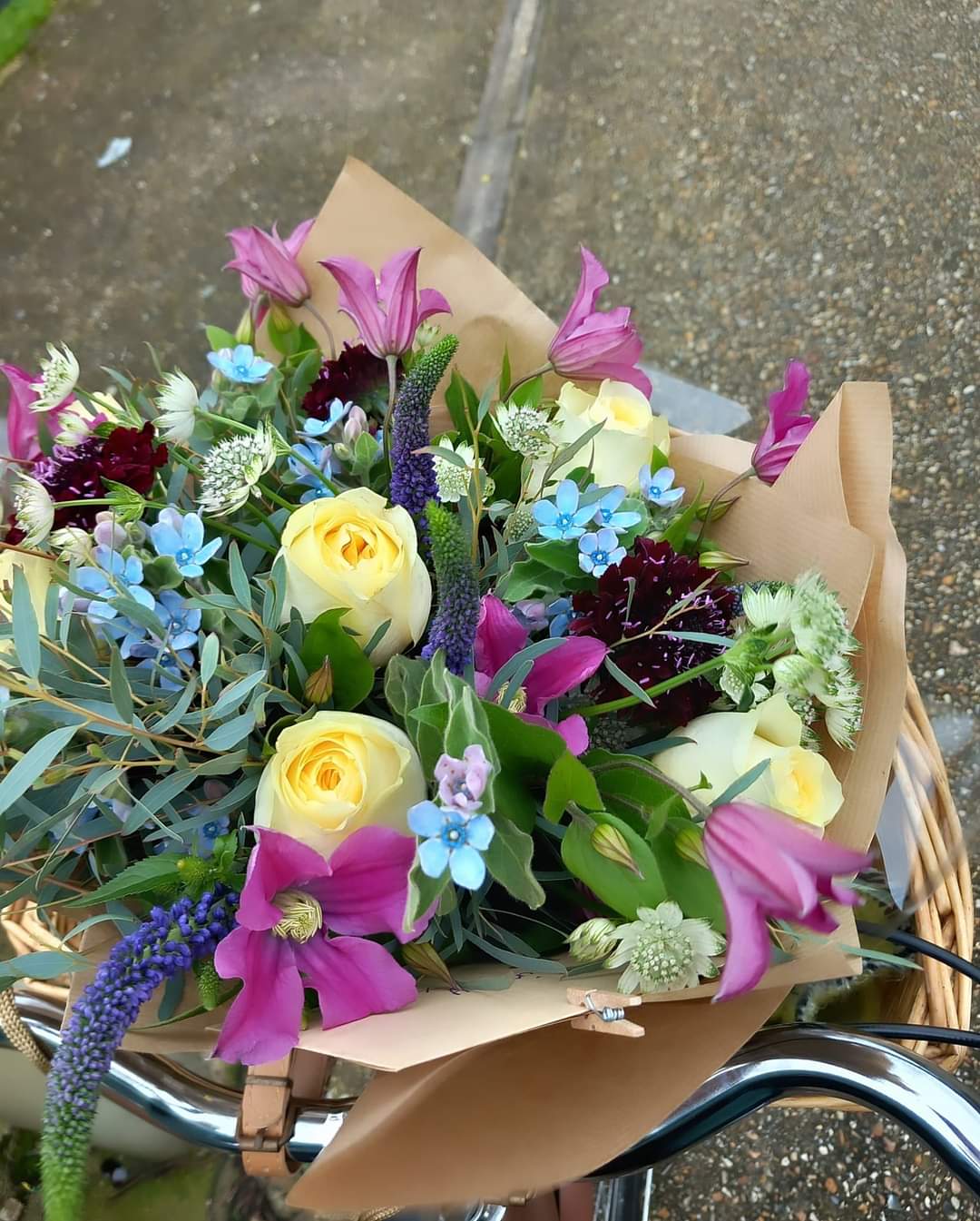 Flower bouquet garden style purple clematis, eucalyptus cream roses purple veronica blue oxy gift wrapped in brown paper